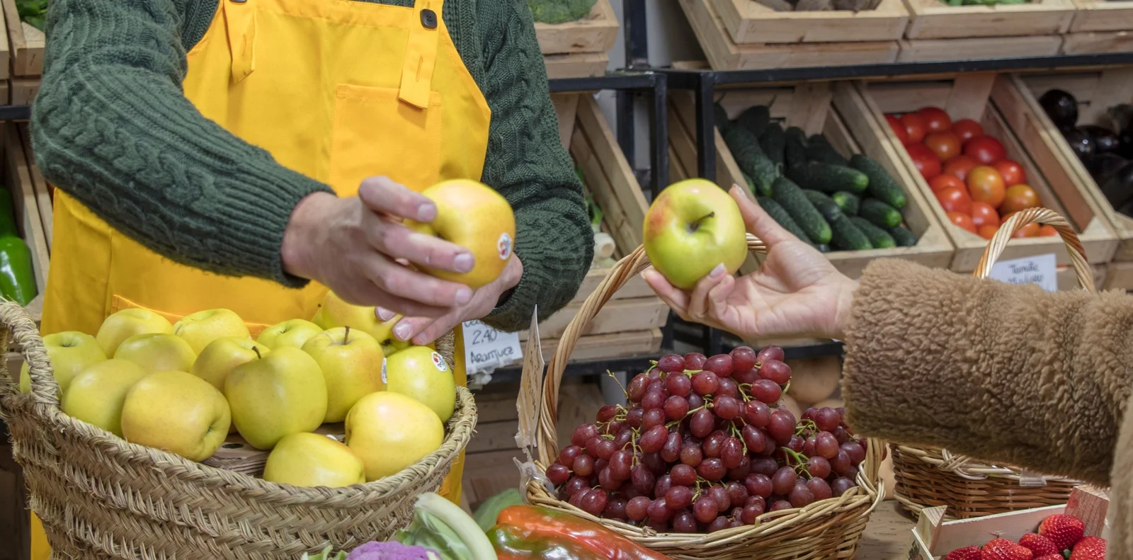 Personal de una tienda seleccionando manzanas frescas para un cliente, ejemplo de evaluación de la demanda y preferencias locales